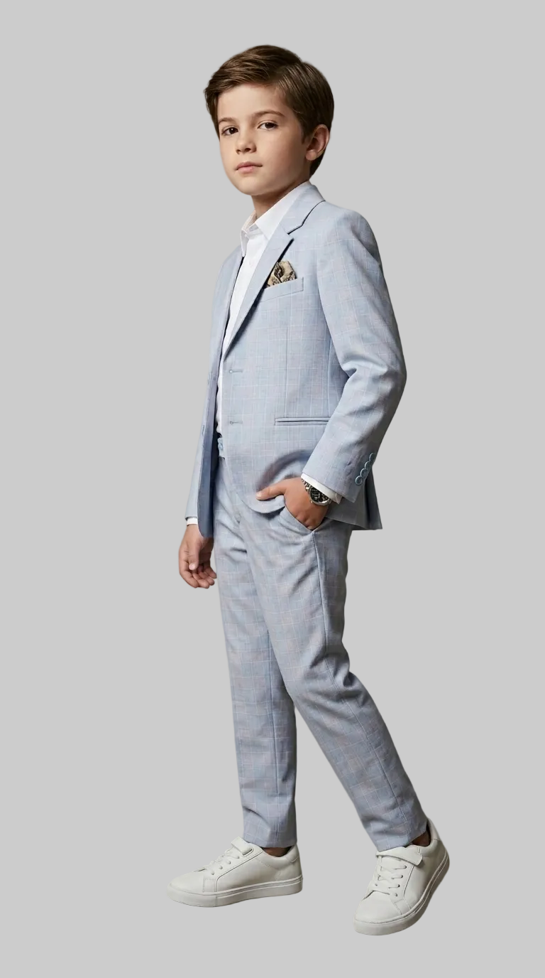 Young boy in a light blue suit standing against a plain background