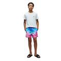 Person wearing a white t-shirt and colorful tie-dye shorts on a white background