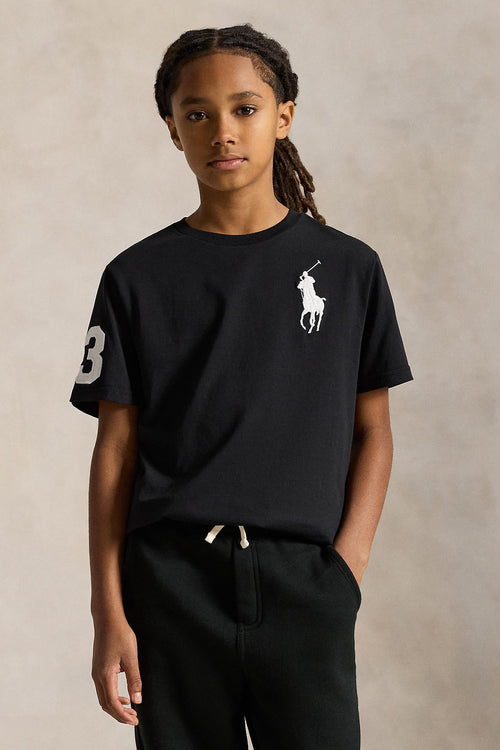 Child wearing a black t-shirt with a logo on a beige background