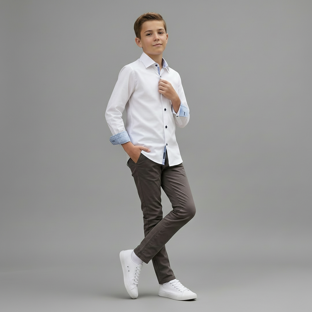 Young boy wearing a white shirt with rolled-up sleeves and brown pants on a gray background