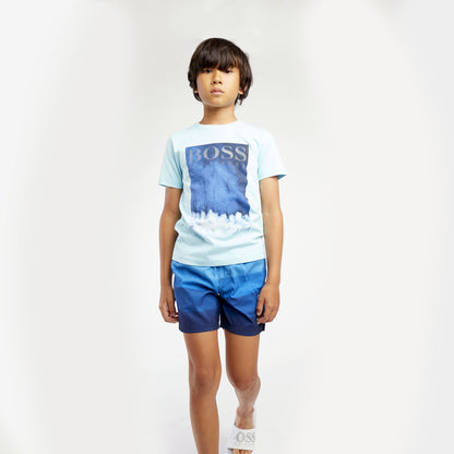Boys wearing Graphic BOSS short sleeve t-Shirt.  Silver BOSS logo on image . Light blue t-shirt with shaded blues in graphic. Slim Fit. 100% cotton
